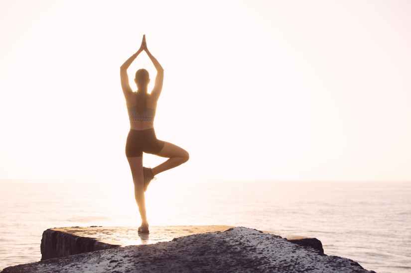 woman doing yoga pose facing sea